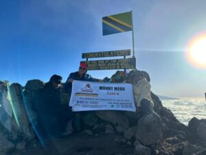 Summit Sunrise. A magical moment at the peak of Mount Meru with the sun rising behind Kilimanjaro.